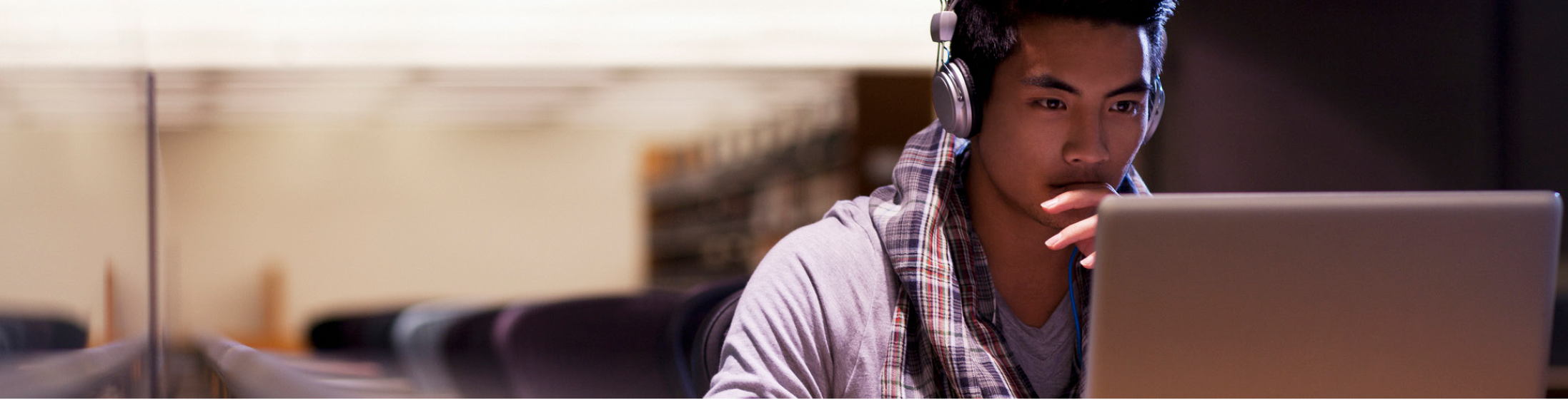 Young adult with headphones working on a laptop
